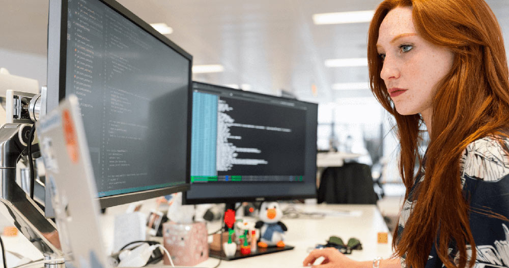 A engineer coding in on two monitors.